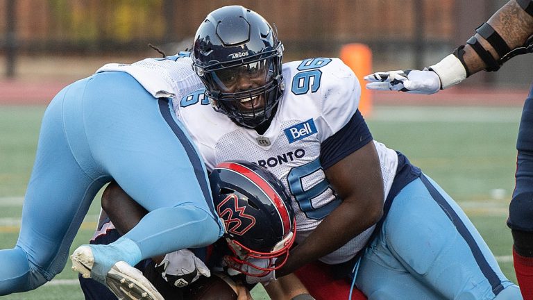 Montreal Alouettes quarterback Trevor Harris, bottom, is brought down by Toronto Argonauts' Sam Acheampong (96) during first half CFL football action in Montreal, Saturday, October 22, 2022. (Graham Hughes/AP)