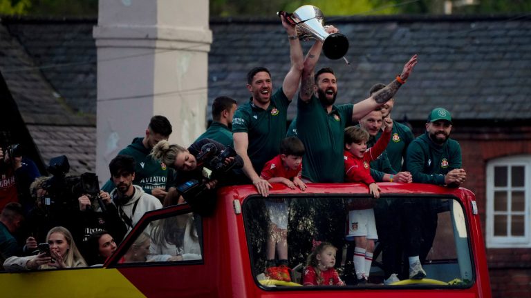 Members of the Wrexham FC soccer team ride on an open top bus as they celebrate promotion to the Football League in Wrexham, Wales, Tuesday, May 2, 2023. (Jon Super/AP) 