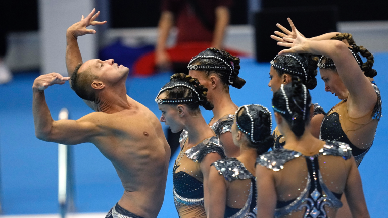 Bill May, left, leads the United States team out to compete in the team acrobatic of artistic swimming at the World Swimming Championships in Fukuoka, Japan, Saturday, July 15, 2023. Largely unoticed by the general public, men have been participating in artistic swimming, formerly known as synchronized swimming, for decades. (AP Photo/David J. Phillip)