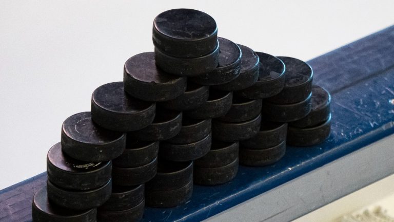 A stack of hockey pucks is set on a bench. (Joseph Weiser/Icon Sportswire via Getty Images)