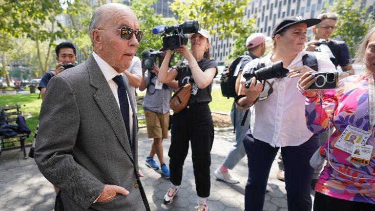 Tavistock founder Joe Lewis, left, is surrounded by photographers as he leaves Manhattan federal court, Wednesday, July 26, 2023, in New York. Lewis pleaded not guilty in New York to insider trading charges alleging that he fed corporate secrets to romantic partners, personal assistants, friends and his pilots, earning them millions of dollars illegally. (Mary Altaffer/AP)