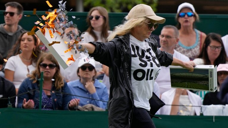 A Just Stop Oil protester runs onto Court 18 and releases confetti and a jigsaw puzzle on day three of the Wimbledon tennis championships in London, Wednesday, July 5, 2023. (Alastair Grant/AP)