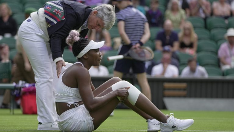 Officials assist after Venus Williams of the US slipped as she plays Ukraine's Elina Svitolina in a first round women's singles match on day one of the Wimbledon tennis championships in London, Monday, July 3, 2023. (Kin Cheung/AP)