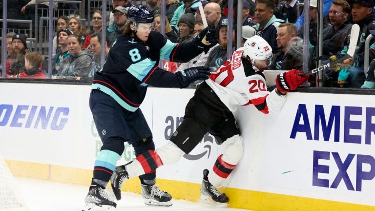 Seattle Kraken defenseman Cale Fleury (8) checks New Jersey Devils center Michael McLeod (20) during the first period of an NHL hockey game, Thursday, Jan. 19, 2023, in Seattle. (John Froschauer/AP)