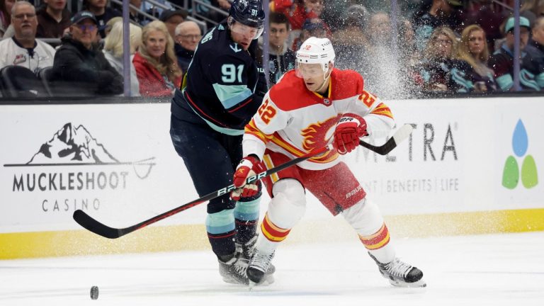 Calgary Flames center Trevor Lewis (22) skates to the puck, beating Seattle Kraken right wing Daniel Sprong (91) to it during the second period of an NHL hockey game Friday, Jan. 27, 2023, in Seattle. (John Froschauer/AP)