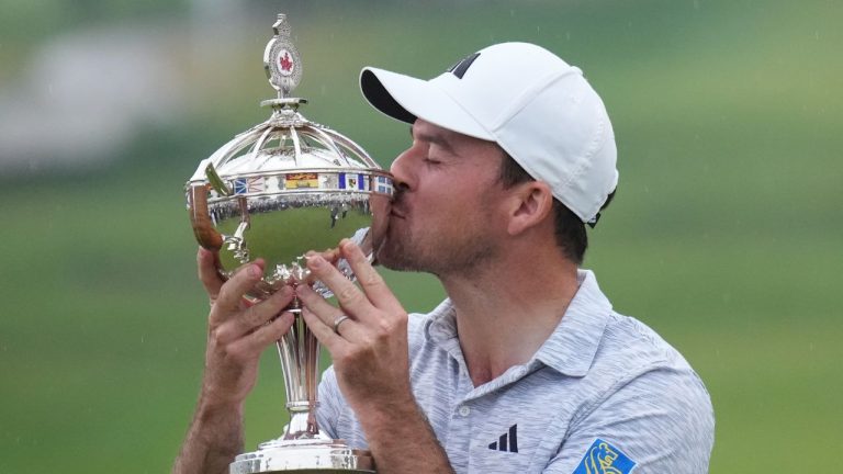 Nick Taylor, of Canada, kisses the trophy after winning the Canadian Open championship on the fourth playoff hole against Tommy Fleetwood, of Southport, U.K., in Toronto on Sunday, June 11, 2023. (Nathan Denette/CP Photo)