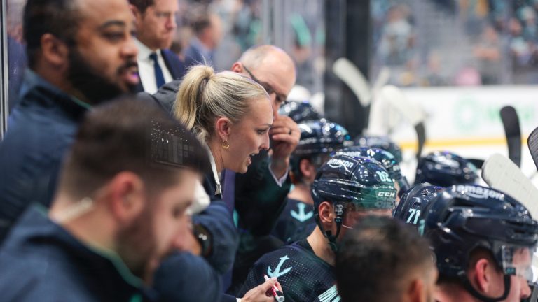 Jessica Campbell, centre, assistant coach for the Coachella Valley Firebirds, works alongside Seattle Kraken coaches behind the bench during the second period of an NHL preseason hockey game against the Calgary Flames, Monday, Sept. 25, 2023, in Seattle. (Jason Redmond/AP)