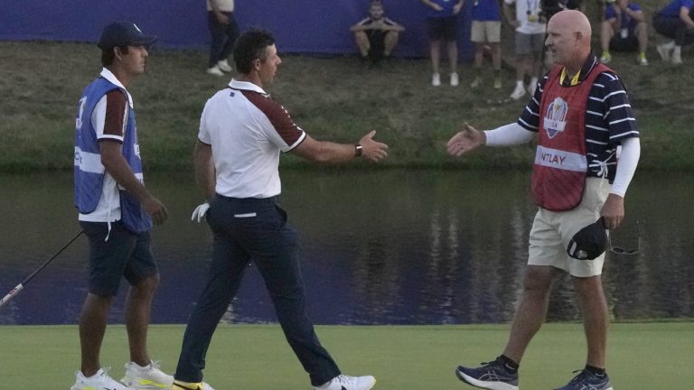 Europe's Rory Mcilroy, centre, goes to shake hands with Patrick Cantlay's caddie, Joe LaCava, on the 18th green following the end of during the afternoon Fourballs matches at the Ryder Cup golf tournament at the Marco Simone Golf Club in Guidonia Montecelio, Italy, Saturday, Sept. 30, 2023. (Alessandra Tarantino/AP)