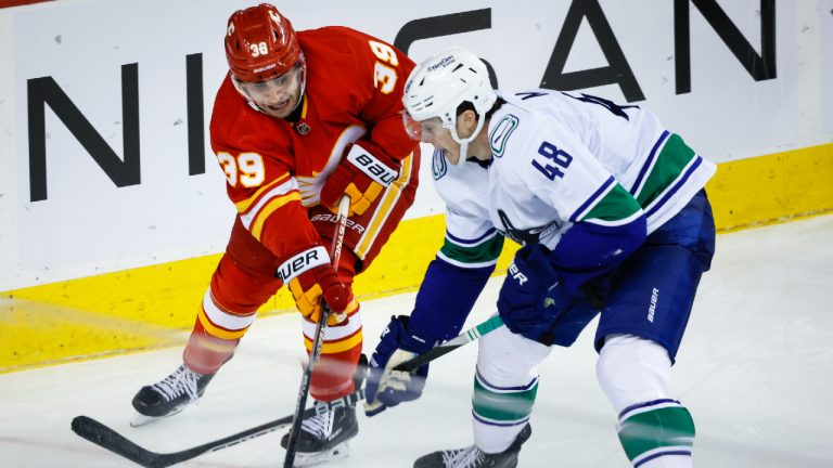 Vancouver Canucks' Cole McWard, right, checks Calgary Flames forward Matt Coronato during third period NHL preseason hockey action in Calgary, Sunday, Sept. 24, 2023. (Jeff McIntosh/CP)