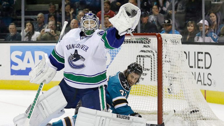 Vancouver Canucks goalie Cory Schneider (35) catches the puck in front of San Jose Sharks right wing Adam Burish (37) during the first period of an NHL hockey game in San Jose, Calif., Monday, April 1, 2013. (Jeff Chiu/AP)