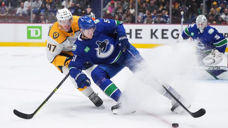 Vancouver Canucks' Tyler Myers (57) and Nashville Predators' Michael McCarron (47) vie for the puck during the first period of an NHL hockey game in Vancouver, on Saturday, November 5, 2022. (Darryl Dyck/CP)