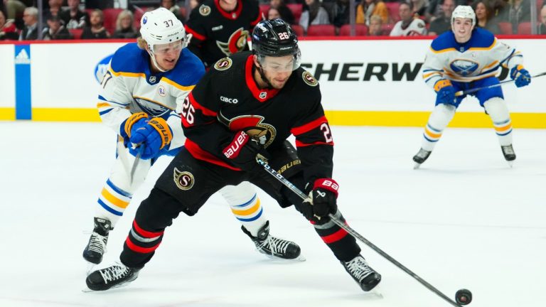 Ottawa Senators defenceman Erik Brannstrom (26) protects the puck from Buffalo Sabres centre Casey Mittelstadt (37) during first period NHL hockey action. (Sean Kilpatrick/CP)