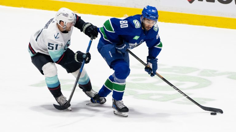 Vancouver Canucks' Arshdeep Bains (80) skates away with the puck as Seattle Kraken's Shane Wright (51) defends during the third period of a preseason NHL in Abbotsford, B.C. on Wednesday, Oct. 4, 2023. (Ethan Cairns/CP)