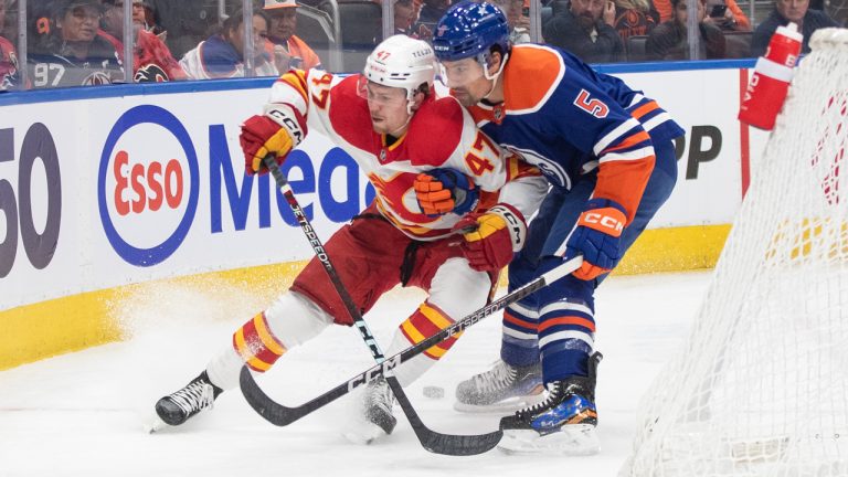 Calgary Flames' Connor Zary (47) and Edmonton Oilers' Cody Ceci (5) battle for the puck during first period NHL preseason action in Edmonton on Wednesday October 4, 2023. (Jason Franson/CP)