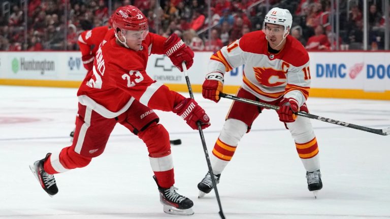 Detroit Red Wings left wing Lucas Raymond (23) shoots as Calgary Flames center Mikael Backlund (11) defends in the first period of an NHL hockey game Sunday, Oct. 22, 2023, in Detroit. (Paul Sancya/AP)