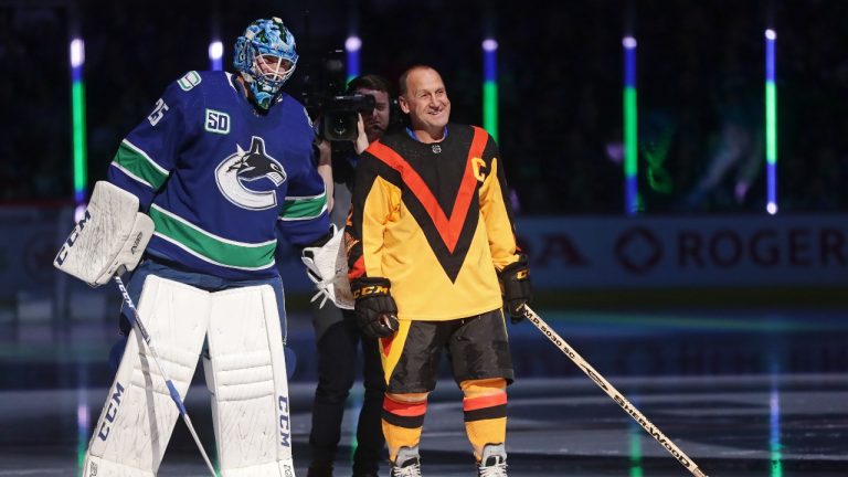 Vancouver Canucks goalie Jacob Markstrom, of Sweden, stands next to former Canucks player Stan Smyl during a ceremony prior to an NHL hockey game. (Darryl Dyck/CP)