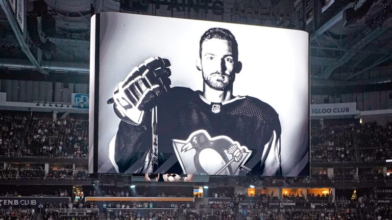 The Pittsburgh Penguins and Anaheim Ducks gather at center ice, before an NHL hockey game in Pittsburgh, Monday, Oct. 30, 2023, to honor former Penguin player Adam Johnson, shown on scoreboard, who died in while playing in an English hockey league game. (Gene J. Puskar/AP)