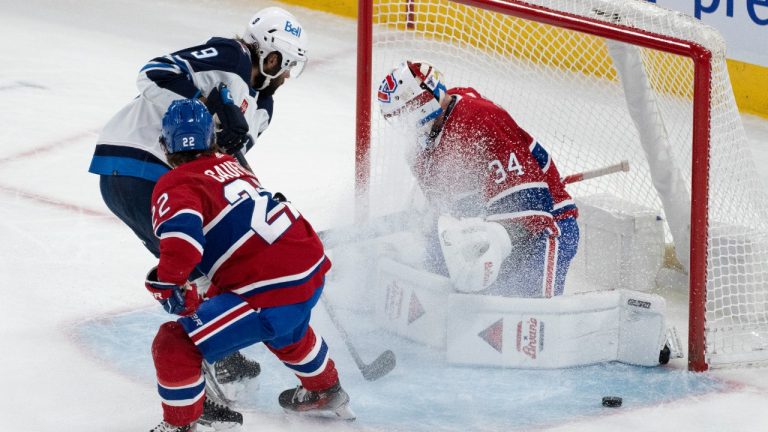 Montreal Canadiens goaltender Jake Allen (34) makes a save against Winnipeg Jets' Alex Iafallo (9) as Canadiens' Cole Caufield (22) skates in during first period NHL hockey action in Montreal on Saturday, Oct. 28, 2023. (Christinne Muschi/CP)