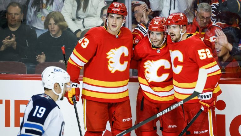 Winnipeg Jets forward David Gustafsson, left, skates past as Calgary Flames Matthew Coronato, centre right, celebrates his goal with teammates Adam Ruzicka, centre left, and defenceman MacKenzie Weegar during third period NHL preseason hockey action in Calgary, Alta., Monday, Oct. 2, 2023. (Jeff McIntosh/THE CANADIAN PRESS)