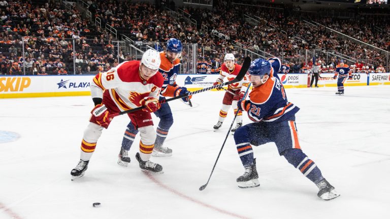 Calgary Flames' Nikita Zadorov (16) and Edmonton Oilers' Adam Erne (21) battle for the puck during second period NHL preseason action in Edmonton on Wednesday October 4, 2023. (Jason Franson/CP)