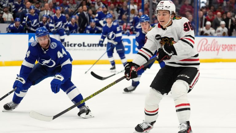 Chicago Blackhawks centre Connor Bedard (98) passes the puck in front of Tampa Bay Lightning defenceman Calvin de Haan (44) during the first period of an NHL hockey game Thursday, Nov. 9, 2023, in Tampa, Fla. (Chris O'Meara/AP)