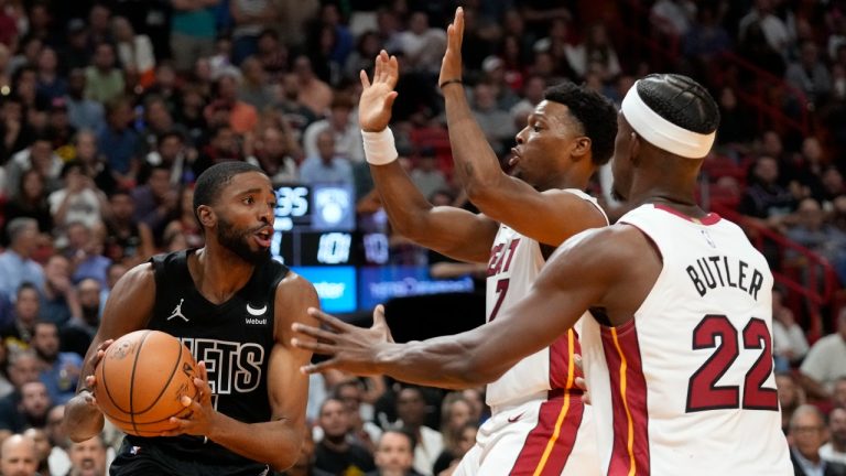 Brooklyn Nets forward Mikal Bridges, left, looks for an opening past Miami Heat guard Kyle Lowry, center, and forward Jimmy Butler (22) during the second half of an NBA basketball game, Wednesday, Nov. 1, 2023, in Miami. (AP Photo/Wilfredo Lee)