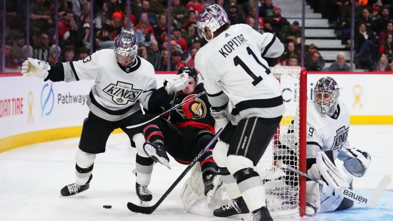 Ottawa Senators right wing Drake Batherson (second left) gets hit to the ice by Los Angeles Kings defenceman Matt Roy (left) as Kings centre Anze Kopitar (11) takes the puck during third period NHL hockey action in Ottawa on Thursday, Nov. 2, 2023. (CP)