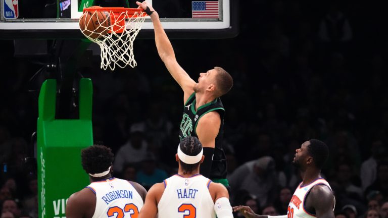 Boston Celtics centre Kristaps Porzingis, top, slams a dunk over the New York Knicks during the first half of an NBA basketball game, Monday, Oct. 13, 2023, in Boston. (Charles Krupa/AP)