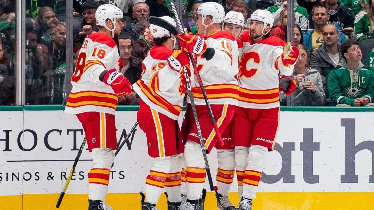 Calgary Flames players gather near left wing A.J. Greer (18) after Greer scored during the second period of an NHL hockey game against the Dallas Stars, Friday, Nov. 24, 2023, in Dallas. (Emil T. Lippe/AP)