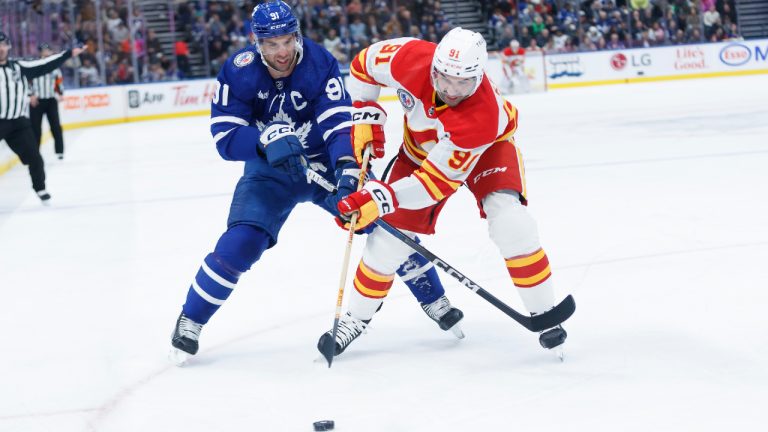 Toronto Maple Leafs centre John Tavares (left) and Calgary Flames centre Nazem Kadri (right) battle for the puck during first period NHL hockey action in Toronto on Friday, Nov. 10, 2023. (Cole Burston/CP)