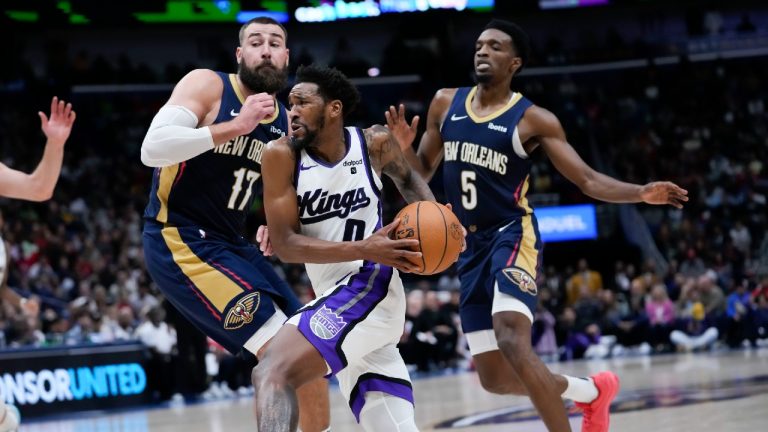 Sacramento Kings guard Malik Monk (0) drives to the basket against New Orleans Pelicans center Jonas Valanciunas (17) and forward Herbert Jones (5) in the second half of an NBA basketball game in New Orleans, Wednesday, Nov. 22, 2023. The Pelicans won 117-112. (Gerald Herbert/AP)