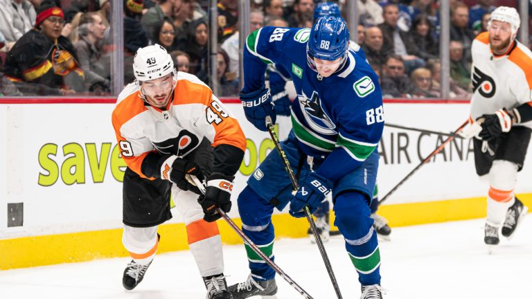 Vancouver Canucks' Nils Aman (right) and Philadelphia Flyers' Noah Cates battle for the puck during second period NHL hockey action in Vancouver, B.C., Saturday, February 18, 2023. (Rich Lam/CP)