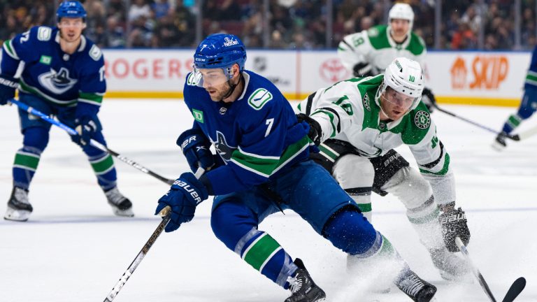 Dallas Stars' Ty Dellandrea (10) grabs Vancouver Canucks' Carson Soucy (7) as he skates with the puck during the first period of an NHL hockey game in Vancouver, on Saturday, Nov. 4, 2023. (Ethan Cairns/CP)