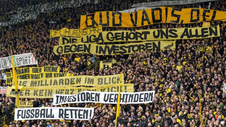 Fans hold up banners protesting against investors in German soccer during the German Bundesliga soccer match between Borussia Dortmund and Union Berlin in Dortmund, Germany, Saturday, April 8, 2023.  (AP Photo/Martin Meissner)