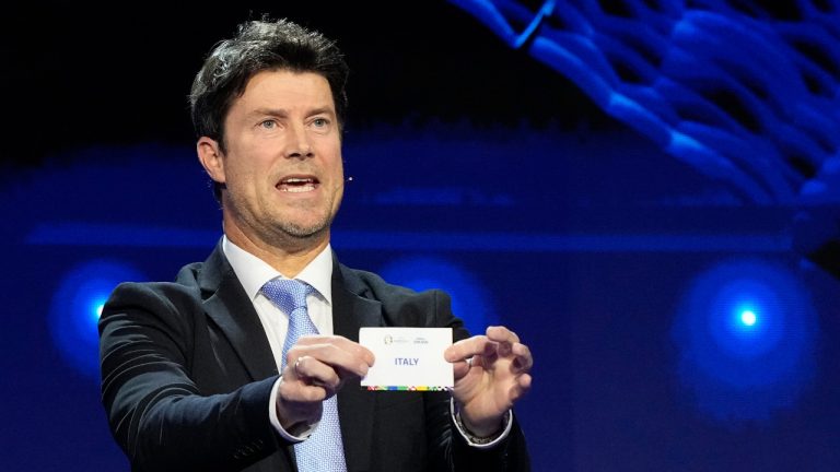 Former soccer player Brian Laudrup holds up the name Italy during the draw for the UEFA Euro 2024 soccer tournament finals in Hamburg, Germany, Saturday, Dec. 2, 2023. (Martin Meissner/AP) 