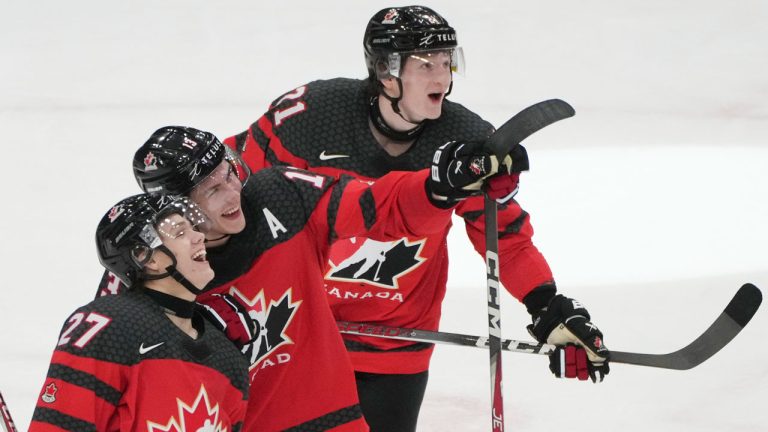 Canada's Easton Cowan (27) watches the replay of his empty net goal with teammates Maveric Lamoureux (13) and Owen Allard (21) during third period hockey action at the IIHF World Junior Hockey Championship in Gothenburg, Sweden, Sunday, Dec. 31, 2023. (Christinne Muschi/CP)