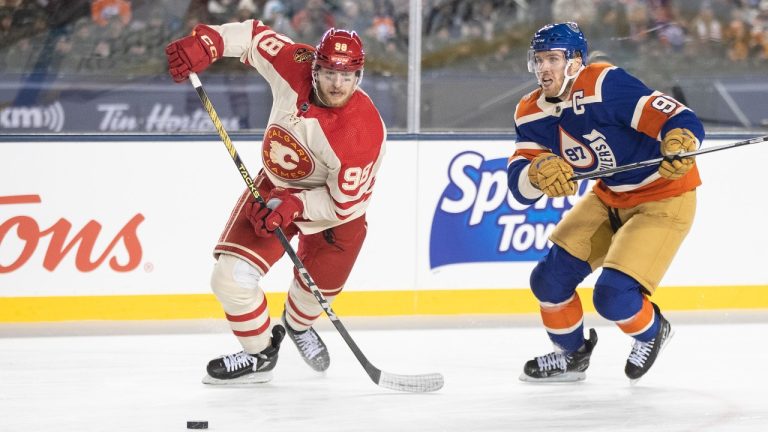 Calgary Flames' Ilya Solovyov (98) and Edmonton Oilers' Connor McDavid (97) chase the puck during third period NHL Heritage Classic action in Edmonton on Sunday October 29, 2023. (Jason Franson/CP)