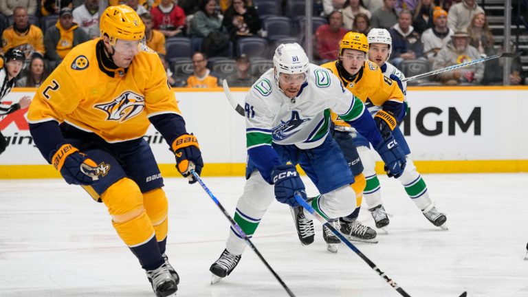 Nashville Predators defenseman Luke Schenn (2) and Vancouver Canucks center Dakota Joshua (81) chase the puck during the first period of an NHL hockey game Tuesday, Dec. 19, 2023, in Nashville, Tenn. (George Walker IV/AP)