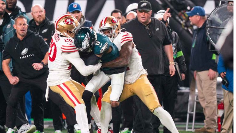 Philadelphia Eagles wide receiver DeVonta Smith (6) with the catch being tackled by San Francisco 49ers linebacker Dre Greenlaw (57) and corner back Ambry Thomas (20) during the NFL football game, Sunday, Dec. 3, 2023, in Philadelphia. This is the play in which San Francisco 49ers linebacker Dre Greenlaw (57) and Philadelphia Eagles head of security Dom DiSandro, right, will be ejected from the game. (Chris Szagola/AP)