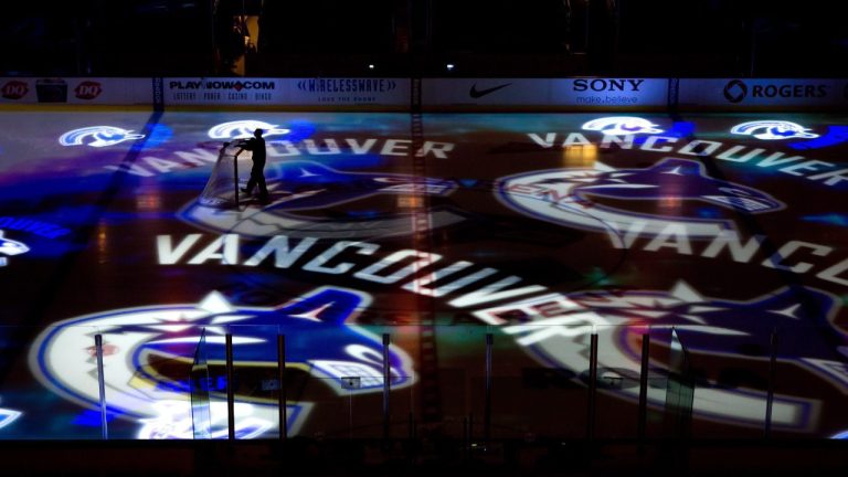 A worker moves a hockey net as Vancouver Canucks team logos are projected on the ice before the team's NHL hockey game against the Detroit Red Wings in Vancouver, B.C., on Thursday February 2, 2012. (Darryl Dyck/CP)