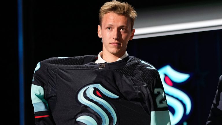 Eduard Sale puts on a Seattle Kraken jersey after being picked by the team during the first round of the NHL hockey draft Wednesday, June 28, 2023, in Nashville, Tenn. (George Walker IV/AP)