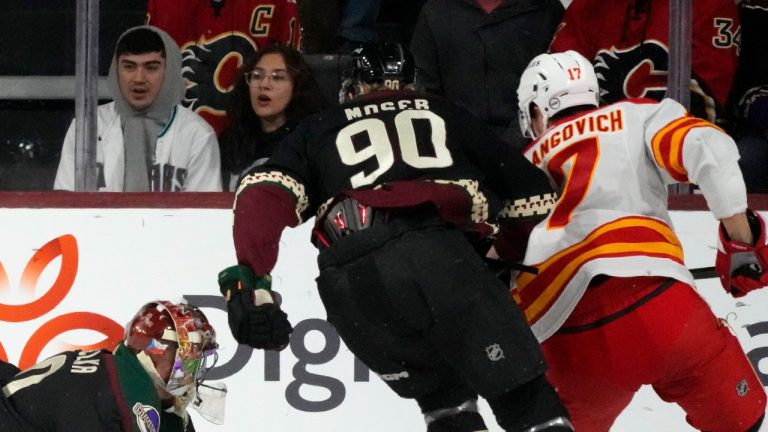 Arizona Coyotes goaltender Karel Vejmelka, left, gives up a goal to Calgary Flames center Yegor Sharangovich (17) as Coyotes defenseman J.J. Moser (90) looks on during the first period of an NHL hockey game Thursday, Jan. 11, 2024, in Tempe, Ariz. (Ross D. Franklin/AP)