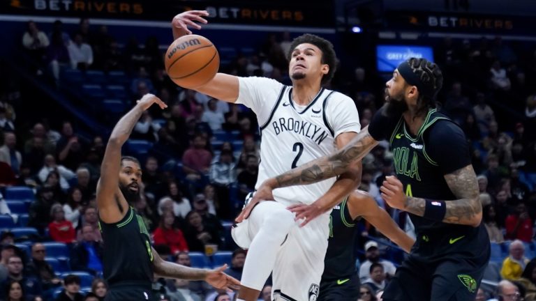 Brooklyn Nets forward Cameron Johnson (2) loses the ball as he drives to the basket between New Orleans Pelicans forward Naji Marshall, left, and forward Brandon Ingram in the first half of an NBA basketball game in New Orleans, Tuesday, Jan. 2, 2024. (AP Photo/Gerald Herbert)