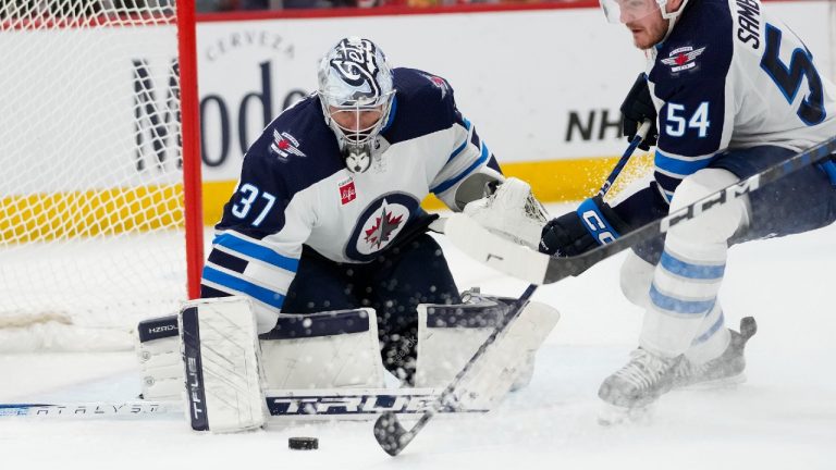 Winnipeg Jets goaltender Connor Hellebuyck, left, gets help with a save from defenseman Dylan Samberg during the third period of the team's NHL hockey game against the Chicago Blackhawks on Wednesday, Dec. 27, 2023, in Chicago. (Erin Hooley/AP)