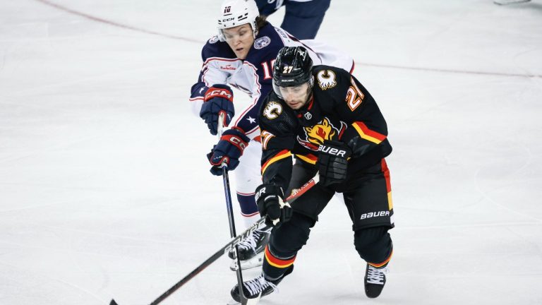 Columbus Blue Jackets forward Dmitri Voronkov (10) and Calgary Flames forward Matthew Coronato (27) chase the puck during first period NHL hockey action in Calgary, Thursday, Jan. 25, 2024. (Jeff McIntosh/THE CANADIAN PRESS)