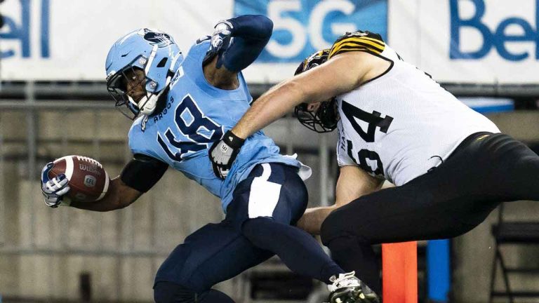 Toronto Argonauts linebacker Wynton McManis (48) scores a touchdown as Hamilton Tiger-Cats offensive linemen Coulter Woodmansey (64) defends during first half CFL football action. (Spencer Colby/THE CANADIAN PRESS)
