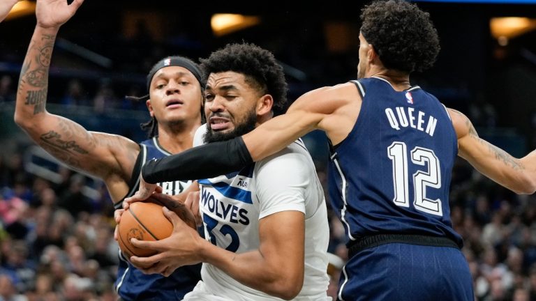 Minnesota Timberwolves center Karl-Anthony Towns, center, makes a moves to get past Orlando Magic forward Paolo Banchero, left, and guard Trevelin Queen (12) during the first half of an NBA basketball game, Tuesday, Jan. 9, 2024, in Orlando, Fla. (AP Photo/John Raoux)