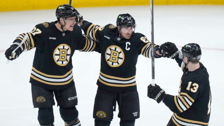 Boston Bruins left wing Brad Marchand (63) celebrates with defenseman Hampus Lindholm (27) and centre Charlie Coyle (13) after scoring against the Vancouver Canucks during the first period of an NHL hockey game Thursday, Feb. 8, 2024, in Boston. (Steven Senne/AP)