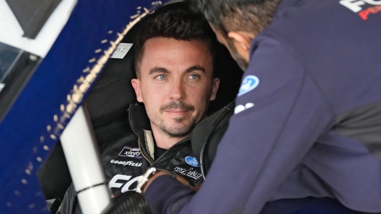 Race car driver and actor Frankie Muniz, left, talks to a crew member before a practice run Friday, Feb. 16, 2024, at Daytona International Speedway in Daytona Beach, Fla. Muniz will attempt to make his NASCAR Xfinity Series debut Saturday. (Chris O'Meara/AP)