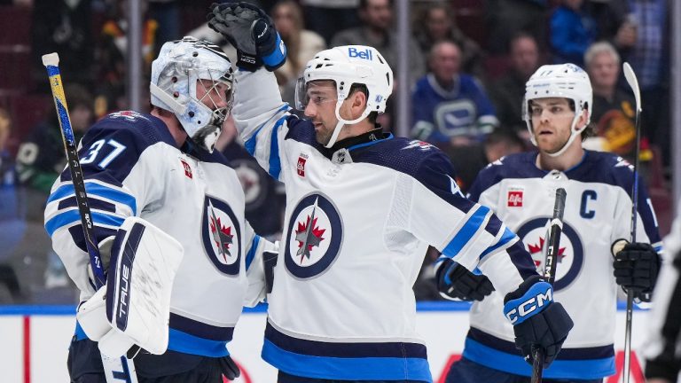 Winnipeg Jets goalie Connor Hellebuyck, from left to right, Neal Pionk and Adam Lowry celebrate after Winnipeg defeated the Vancouver Canucks 4-2 in an NHL hockey game in Vancouver, on Saturday, February 17, 2024. (Darryl Dyck/CP)